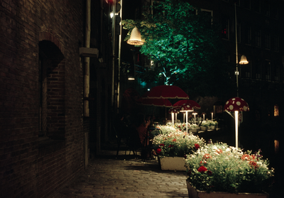 849821 Gezicht op een verlicht terras op de werf aan de Oudegracht te Utrecht, bij avond.